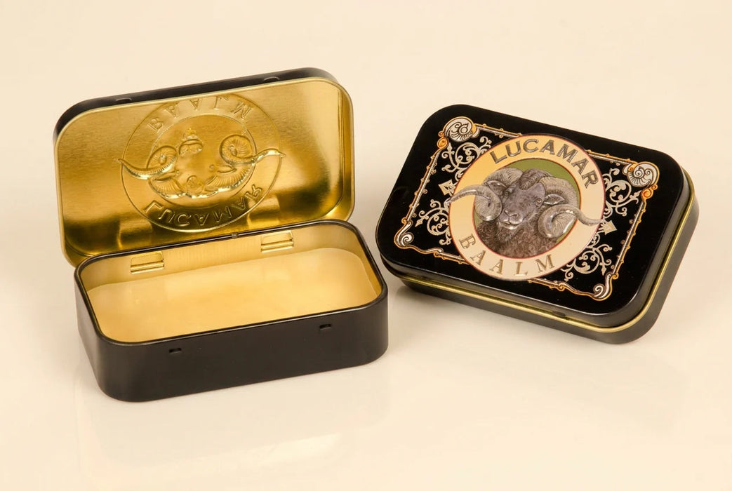 two metal tin cans, one with a gold-colored lid and the other with a black lid, both containing a product.