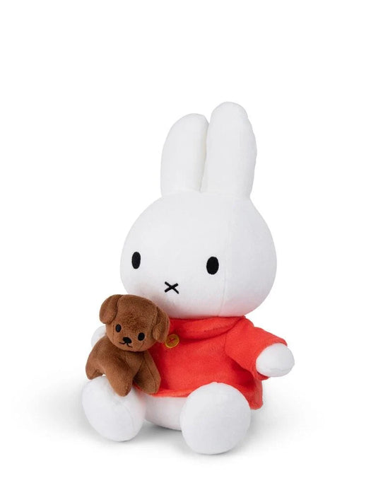 A white stuffed bunny toy wearing a red shirt and holding a brown stuffed dog toy.