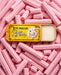 A tin of pink lip balm with a picture of a lamb on it, surrounded by pink lip balm sticks.