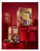 a red tin can with a Christmas-themed design, placed on top of a red gift box, with a red ribbon and other red objects in the background.