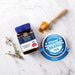 a jar of Manuka Honey, a honey jar, and a honey dipper on a marble surface.