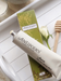 a tube of Antipodes' Honey Mask and a box of the product, along with a honey dipper and a white rose.