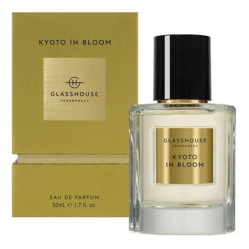 a bottle of Glasshouse Fragrance's Kyoto in Bloom eau de parfum, which is a 50ml eau containing 1.7 fluid ounces. The bottle is placed next to its packaging, which is a gold-colored box with the text "KYOTO IN BLOOM" and "GLASSHOUSE Fragrance" printed on it.