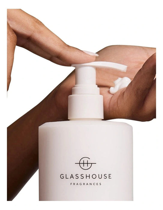 A person's hand applying lotion from a white pump bottle with the "GLASSHOUSE FRAGRANCES" logo.