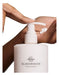 A person's hand applying lotion from a white pump bottle with the "GLASSHOUSE FRAGRANCES" logo.