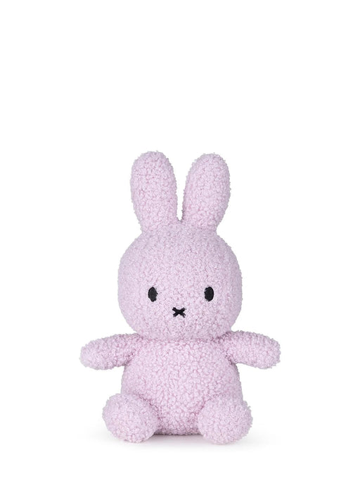 A small, pink stuffed bunny toy is sitting on a white background.