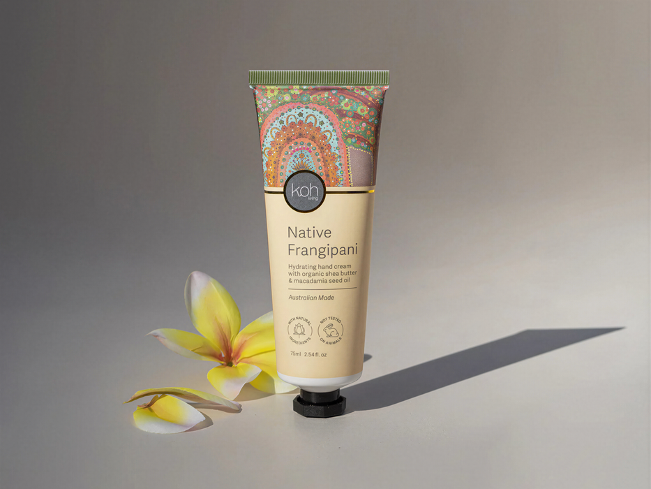 a tube of "Native Frangipani" hand cream, with a yellow flower and some petals on the side, against a plain background.