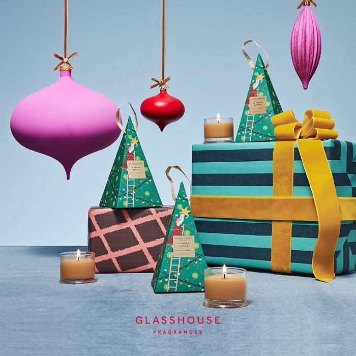 a festive arrangement of Christmas-themed items, including ornaments, candles, and gift boxes, all set against a blue background.