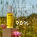 A bottle of "Jurique" face oil, specifically "RARE ROSE FACE OIL", is shown against a blurred background of a field with flowers. The text highlights the oil as a "next-generation face oil" that is "perfect for dehydrated skin, for more supply, smoother skin." The image also states that the oil is " Clinically proven to instantly strengthen skin barrier function in 98% of participants."