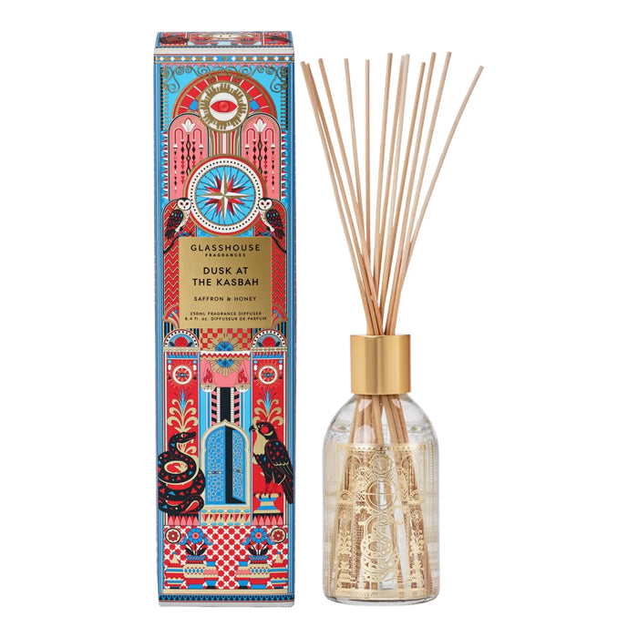 a glass diffuser with a gold-colored cap and a box with a colorful, ornate design.