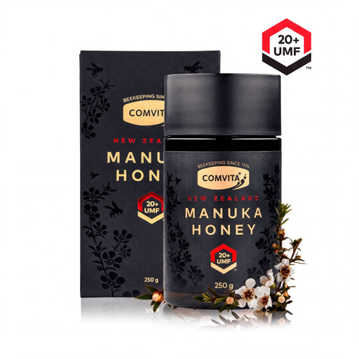 a bottle of Comvita Manuka Honey and its packaging, both of which are black with floral designs.