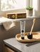 a toothpaste tube, a toothbrush, and a potted plant on a bathroom counter.