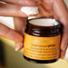 A person's hand is holding a jar of "Antipodes Supernatural SPF50+ Ceramide Silk Facial Sunscreen" cream.
