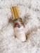 A bottle of "Native Frangipani & Peach Blossom" perfume with a gold cap, placed on a fluffy white surface.