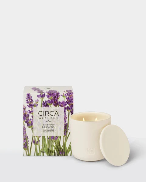 a white candle in a white container with a lid, and a box of the same candle.