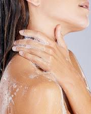 A close-up of a person's shoulder and neck area, with their hands and hair visible.