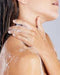 A close-up of a person's shoulder and neck area, with their hands and hair visible.
