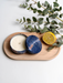 a wooden tray with a candle in a blue tin, a lemon slice, and some greenery.