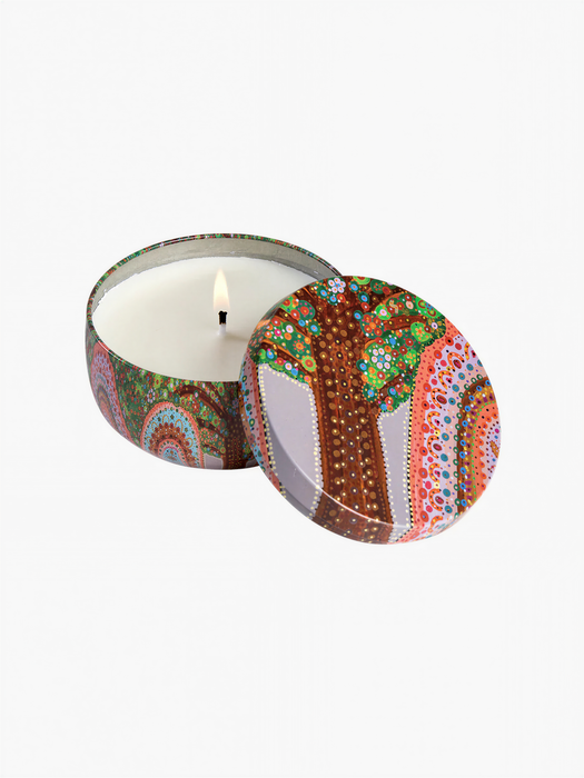 a candle in a decorative tin with a colorful tree design on the lid.