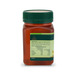 a bottle of honey with a green cap, containing a red liquid.