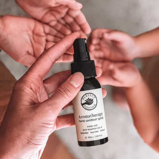 A hand holding a bottle of hand sanitizer spray.