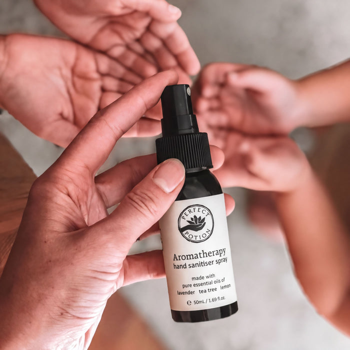 A hand holding a bottle of hand sanitizer spray.