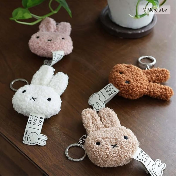 a collection of plush rabbit keychains, each with a tag attached, placed on a wooden surface.
