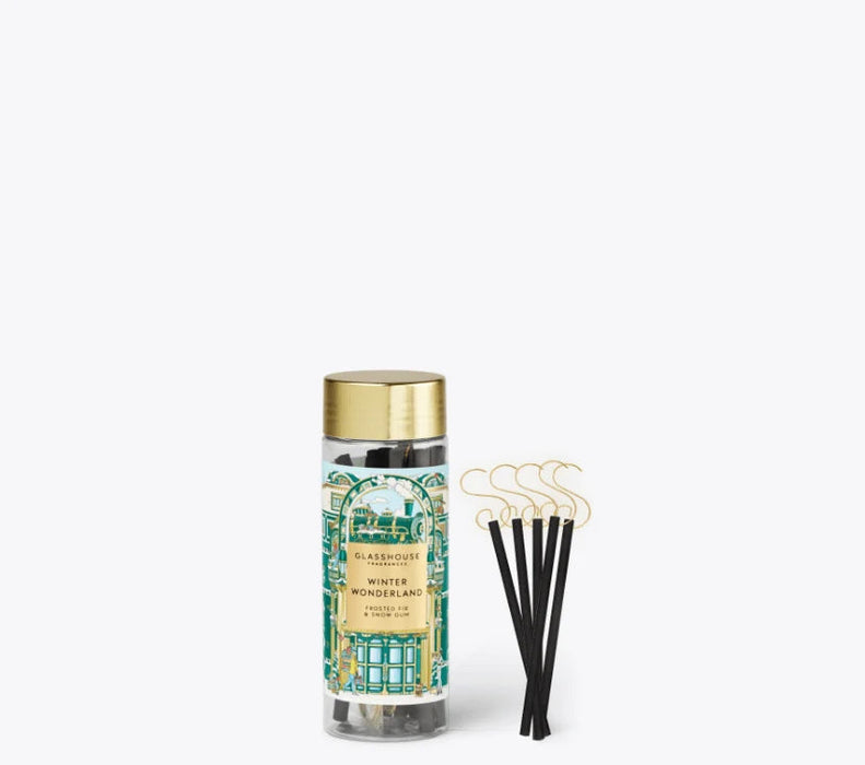A clear glass jar with a gold lid, containing black sticks, and a set of black sticks with gold hooks next to it.