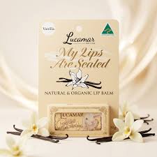 a package of Lucamar My Lips Are Sealed lip balm, with vanilla-flavored scented lip balm inside. The packaging is adorned with a floral design, and there are vanilla-flavored flowers surrounding the package.