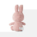 A pink stuffed bunny toy is sitting on a white surface.