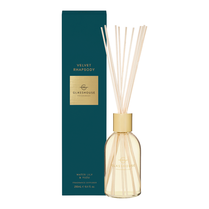 A glasshouse velvet rhapsody water lily fragrance diffuser, with a clear glass bottle containing white sticks and a dark green box with gold lettering.
