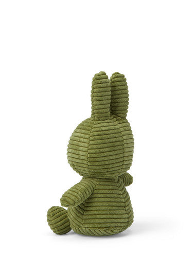 A green stuffed bunny toy is sitting on its back with its arms and legs spread out.