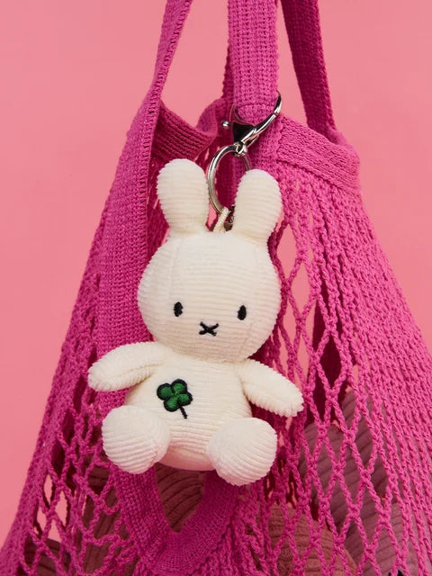 A white stuffed bunny toy is hanging from a pink mesh bag.