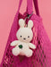 A white stuffed bunny toy is hanging from a pink mesh bag.