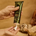 A person's hand is applying a tube of lotion to their face.