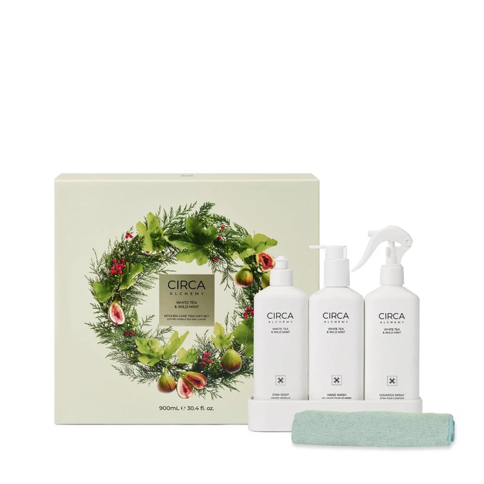 a gift set with three white bottles and a spray bottle, all labeled with the brand name 'CIRCA'. The gift set is presented next to a white box with a wreath design, and there is a green towel placed in front of the gift set.