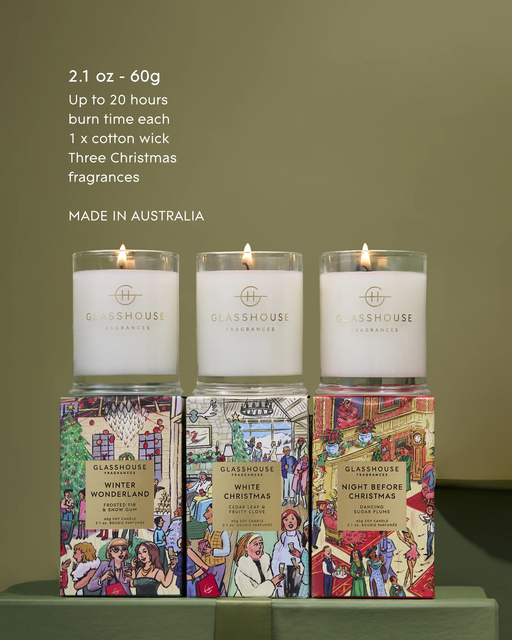 Three candles from the brand Glasshouse, each with different scents, are displayed on a table.