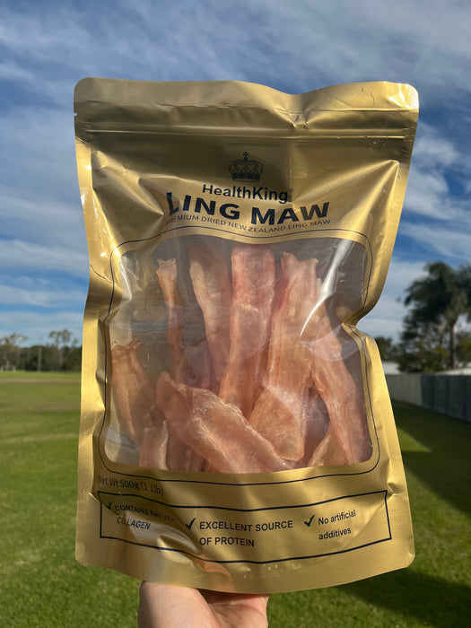 A hand holding a package of bacon strips against a blue sky background.