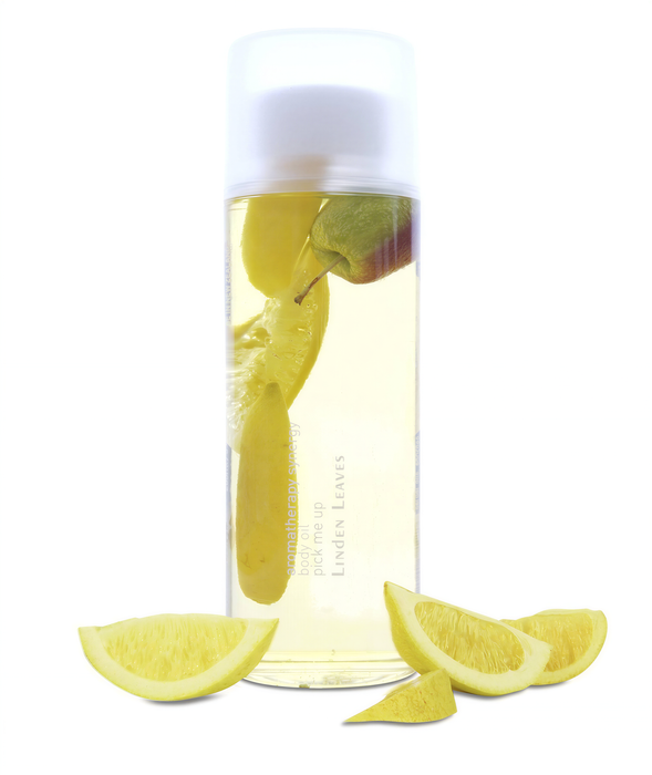 A clear glass bottle filled with a yellow liquid, containing sliced lemons and a green apple floating in it.