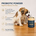 The image is an advertisement for a probiotic powder product for pets. It features a dog sitting on a wooden floor next to a can of the product, with text describing the product's benefits for dogs.