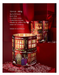 a red candle holder with a winter scene design, placed on a red surface with snow around it.