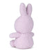 A plush, pink bunny toy is sitting on its back with its arms and legs spread out.