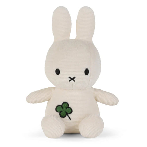 A white stuffed bunny toy with a green clover design on its chest.