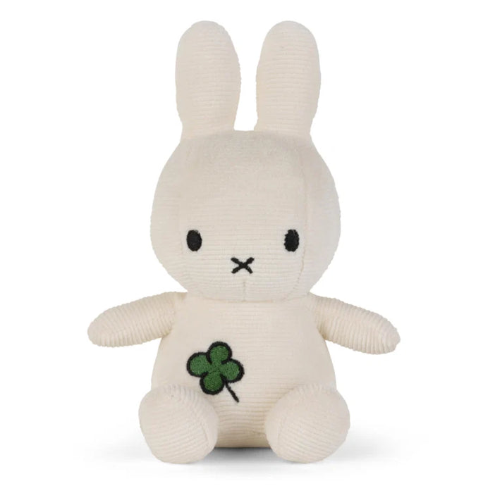 A white stuffed bunny toy with a green clover design on its chest.