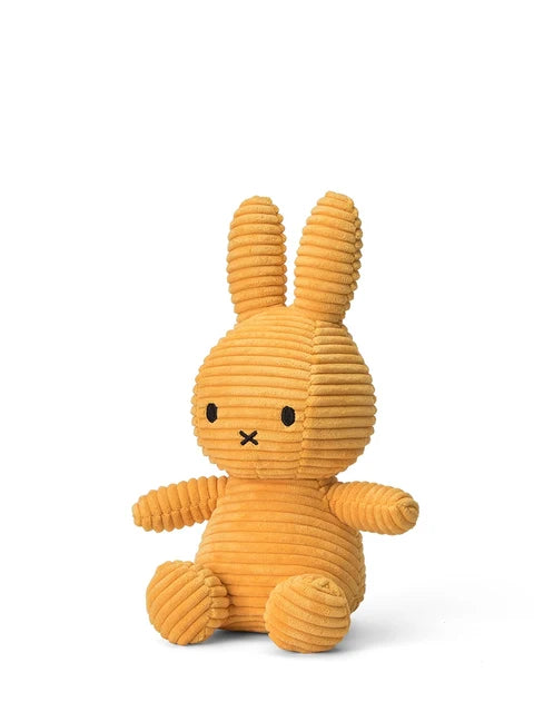 A yellow, furry stuffed bunny toy is sitting on a white background.