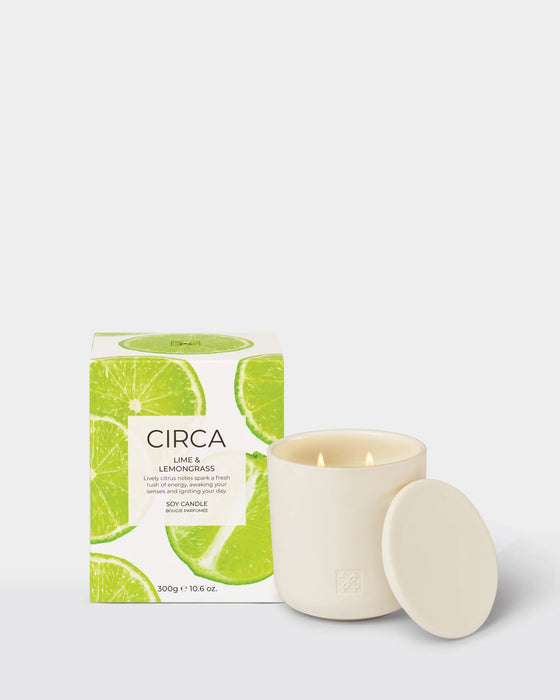 a white ceramic candle with a lime and lemon scent, placed next to its packaging box.