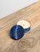 A blue and white ceramic candle holder with a lit candle sits on a wooden surface.