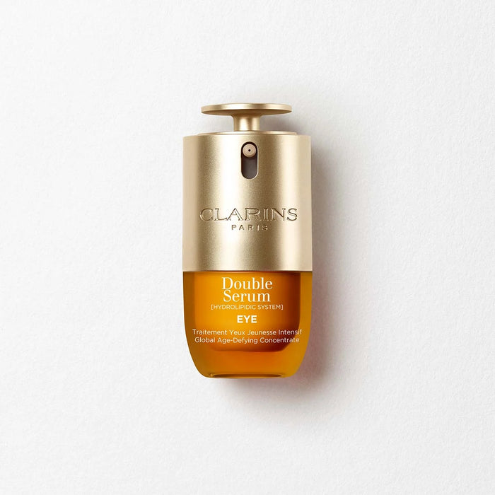 A bottle of double serum eye treatment by Clarins Paris, with a gold cap and a yellow liquid inside.