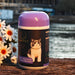 A purple and black jar of cat food with a picture of a cat on it, placed on a wooden surface next to a bouquet of white and orange flowers.