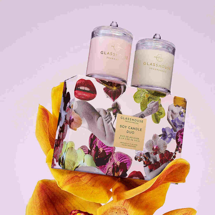 two glass jars with candles, placed on top of a floral box with a vibrant design.